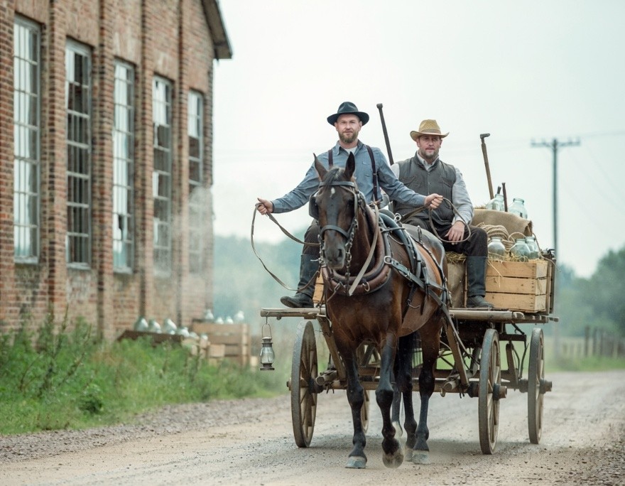 A horse-drawn wagon hauling logs near the settlement sawmill